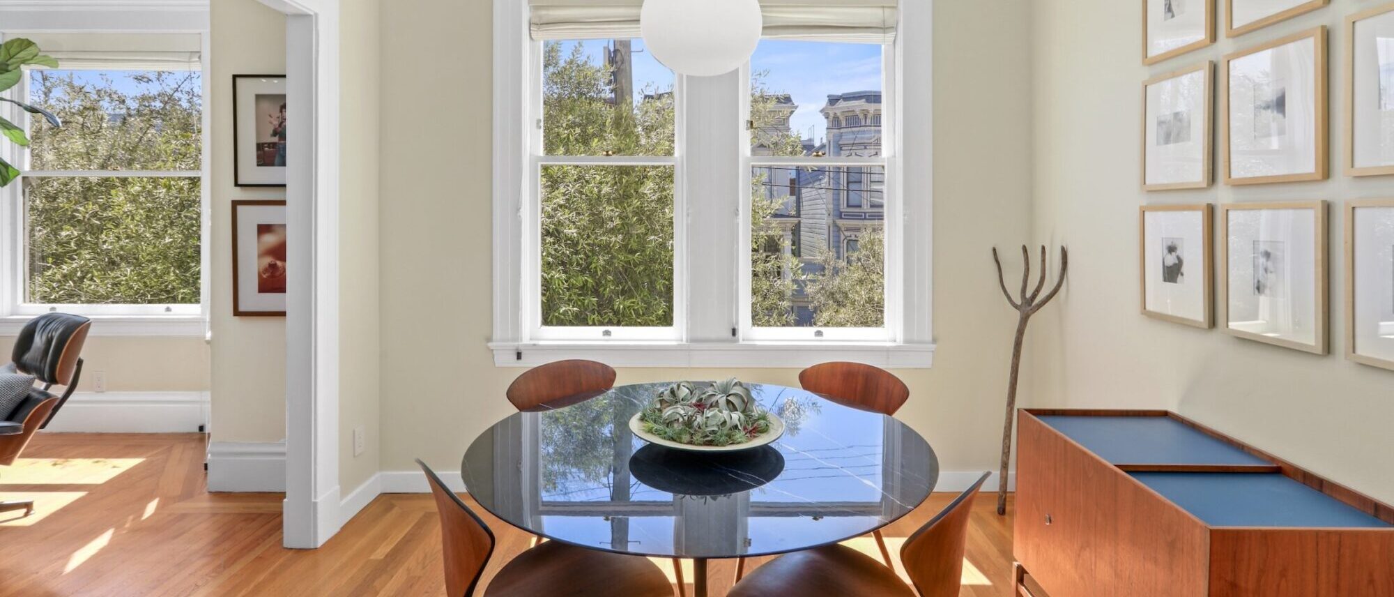 Dining room with round marble table and walnut chairs overlooking Victorian homes at 2696 Bush Street, San Francisco