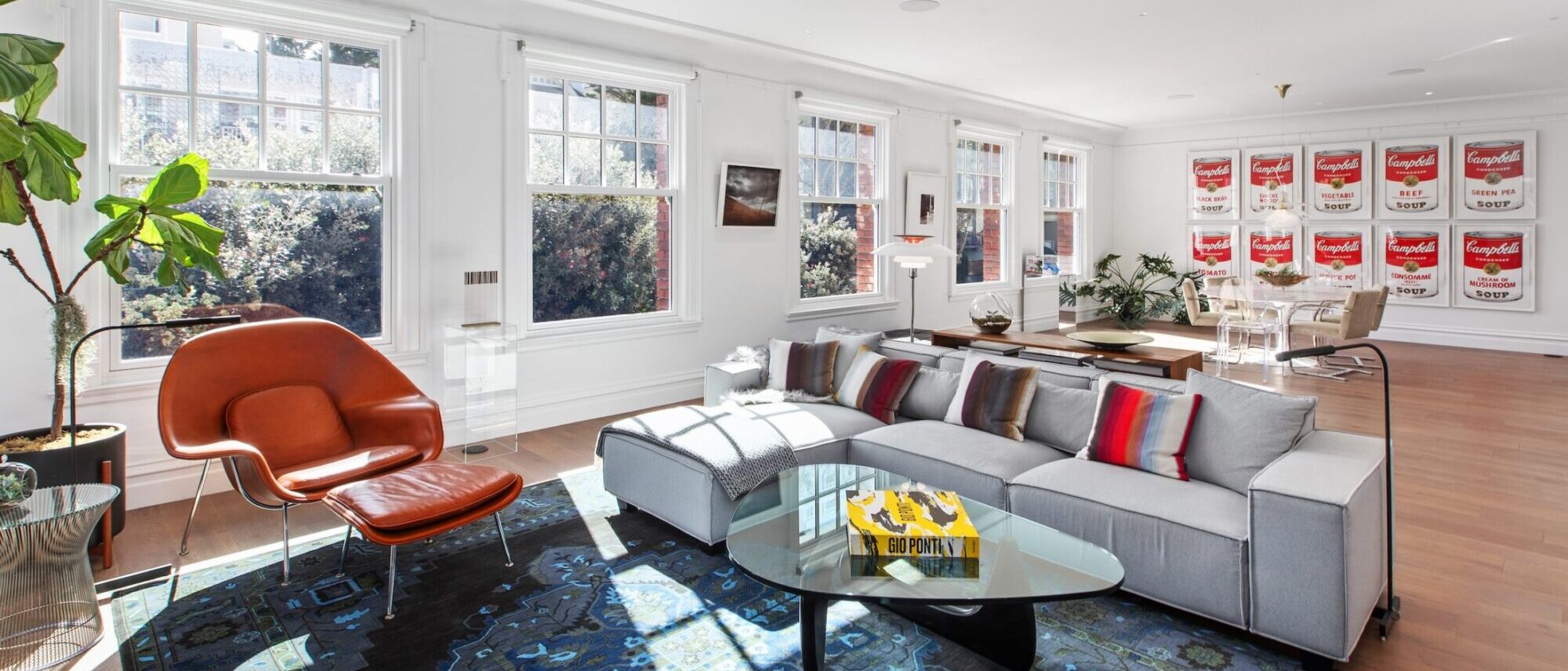 Bright living room with orange lounge chair, gray sectional and Campbell's Soup art wall at 1830 Jackson #B, San Francisco