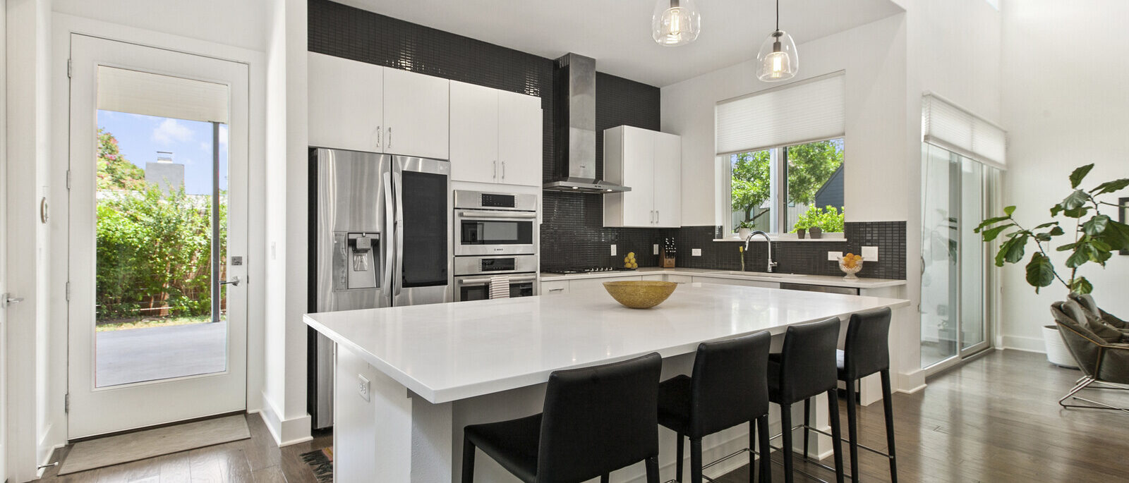 2117 Ann Arbor – Kitchen White kitchen with large quartz island, black bar stools and stainless appliances at 2117 Ann Arbor